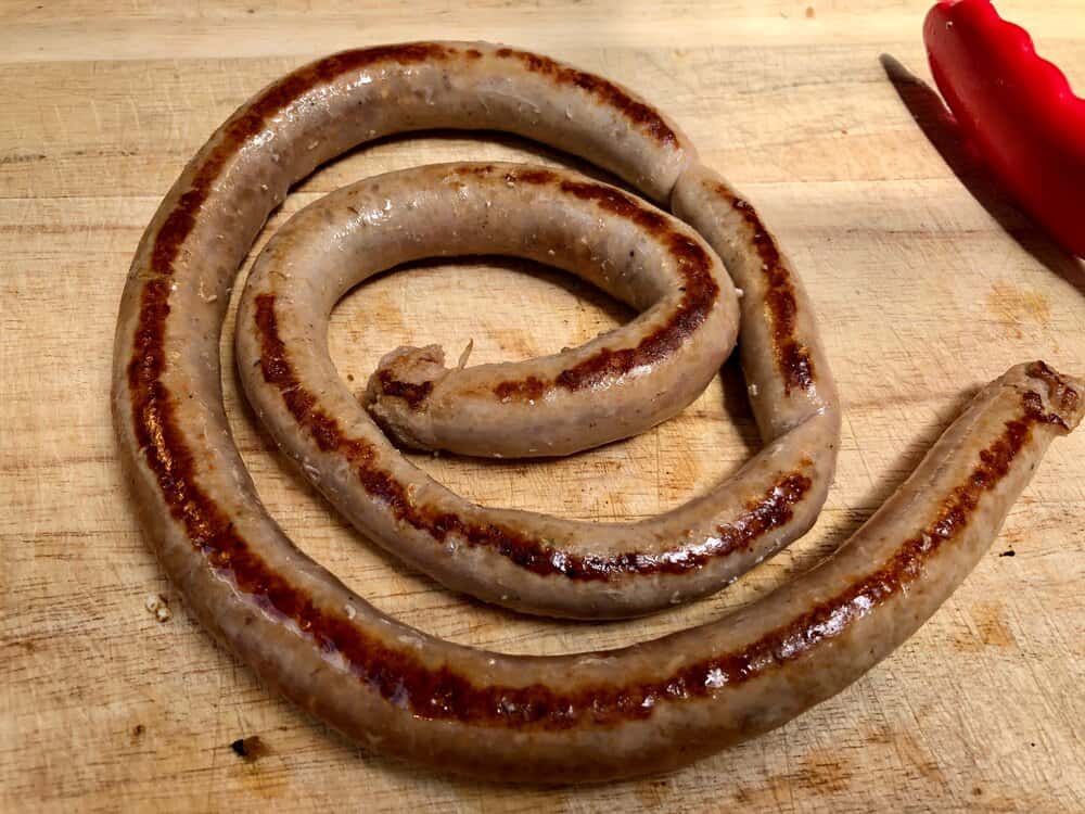 Cooked sausage link rolled up on a cutting board