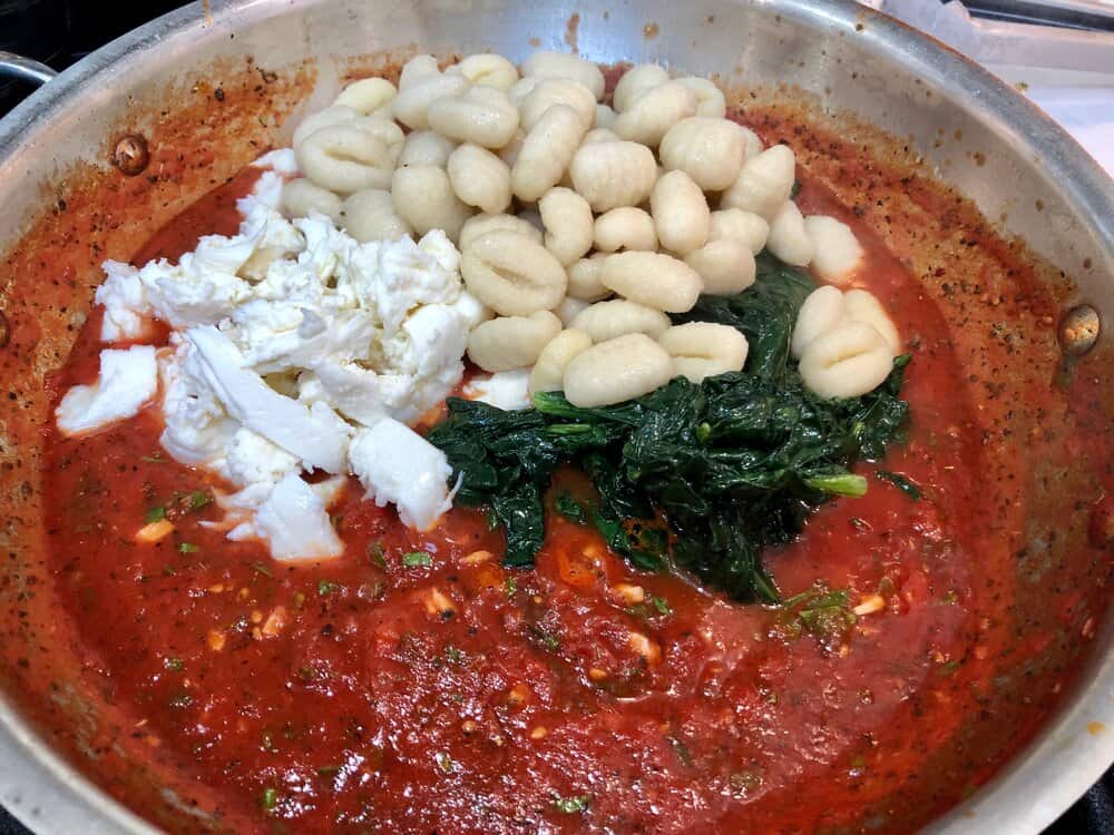 Gnocchi, spinach and mozzarella in tomato sauce in a pan