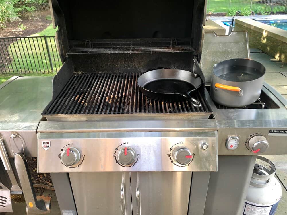 A weber grill with pots and pans laying on top of it