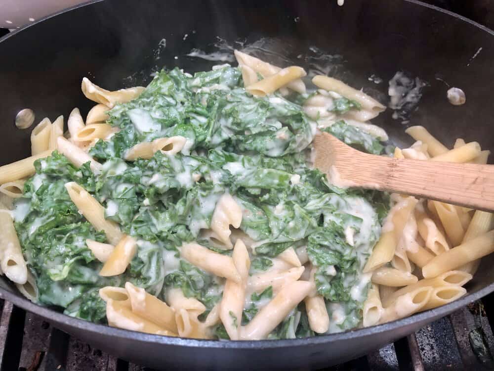 Penne pasta with creamy spinach on top in a pot