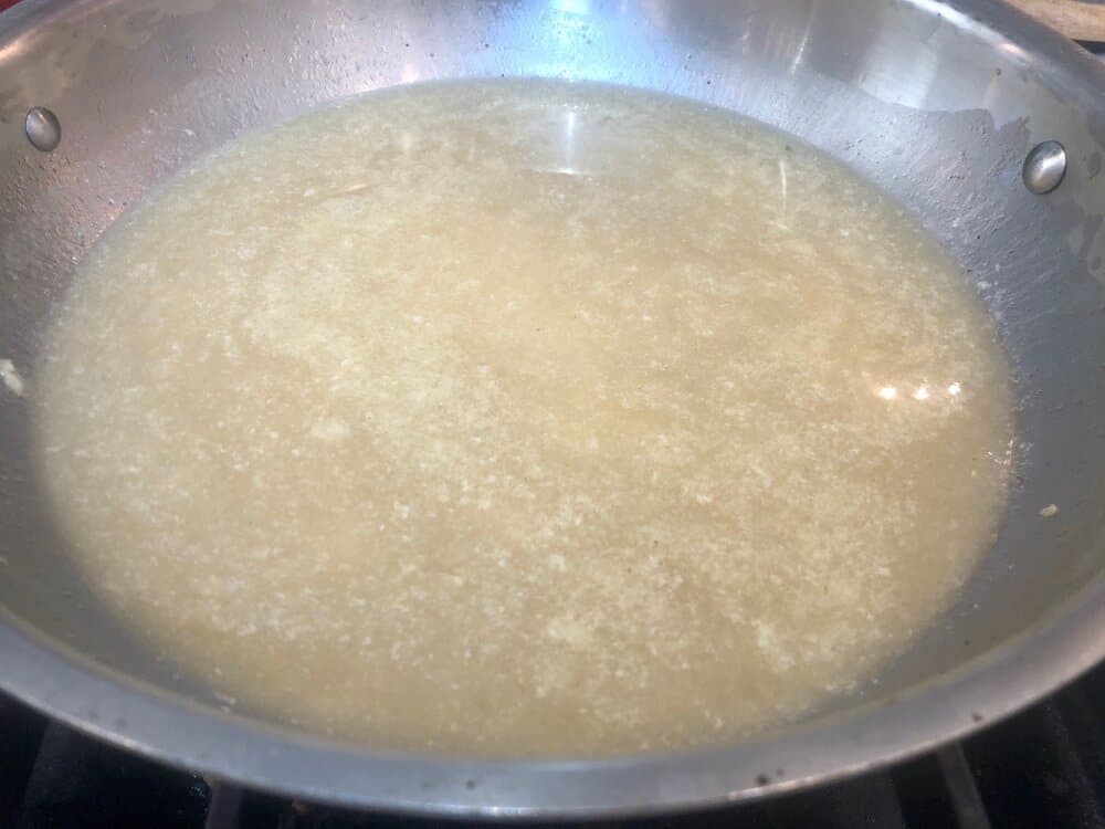 Garlic, wine and chicken broth sauce in a pan