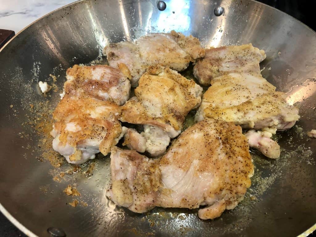 Chicken thighs frying in a pan