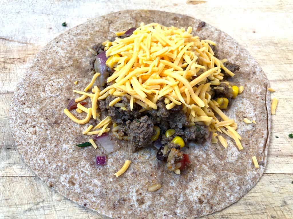 Ground beef topped with cheese on a tortilla