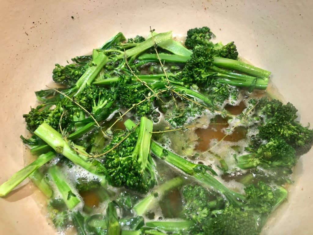 Broccolini cooking in liquid with thyme