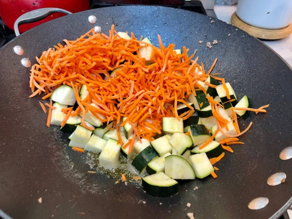 Zucchini and carrots cooking in a wok