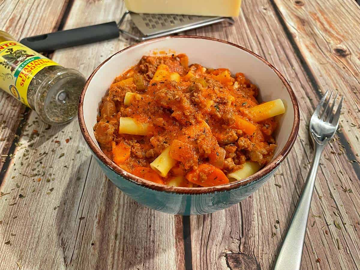 Creamy Bolognese sauce with rigatoni and vegetables in a bowl.