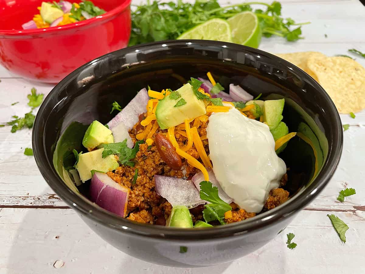 Red kidney bean chili in a bowl with toppings.