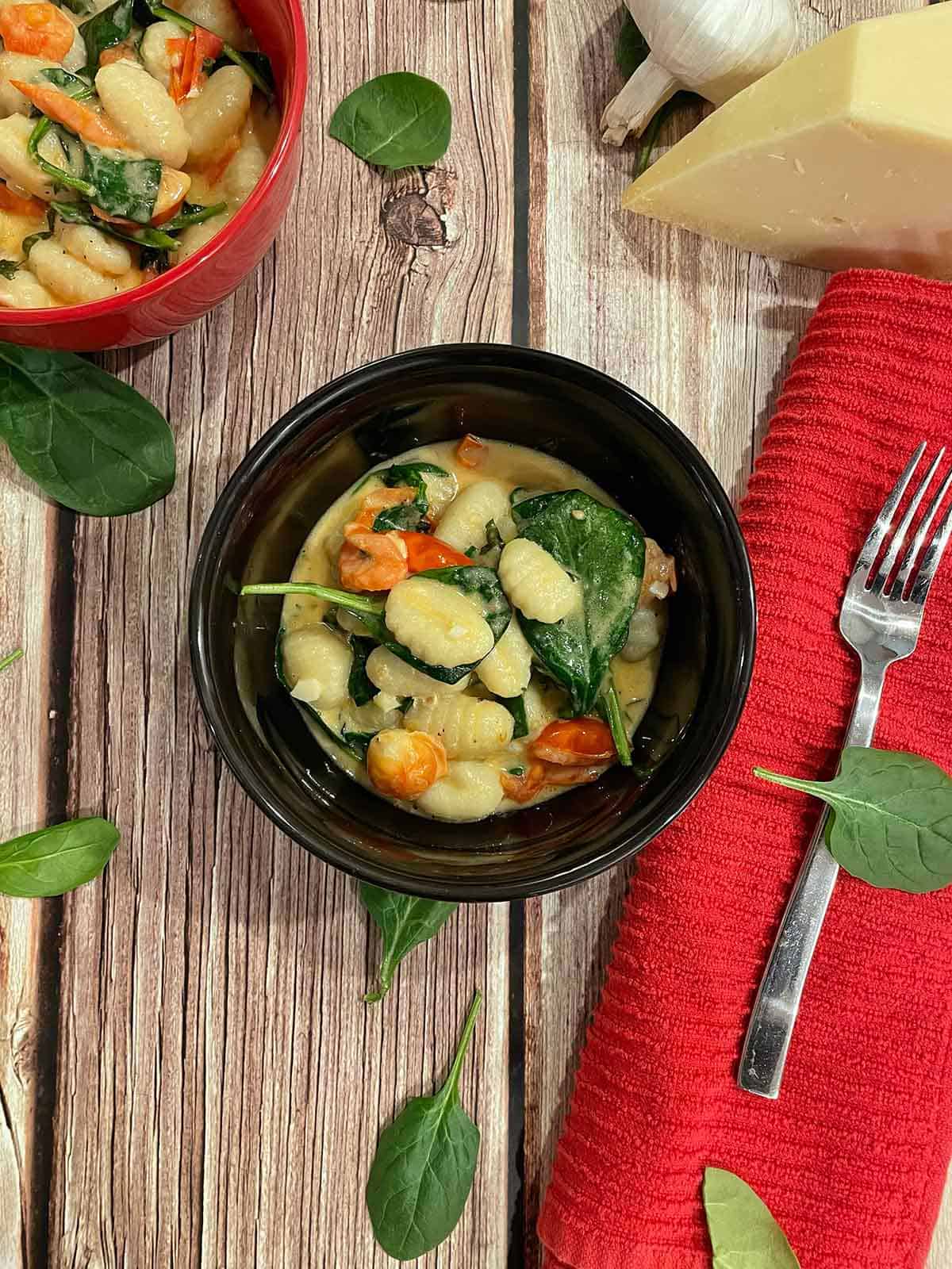 Creamy spinach gnocchi with basil and cherry tomatoes in a bowl.